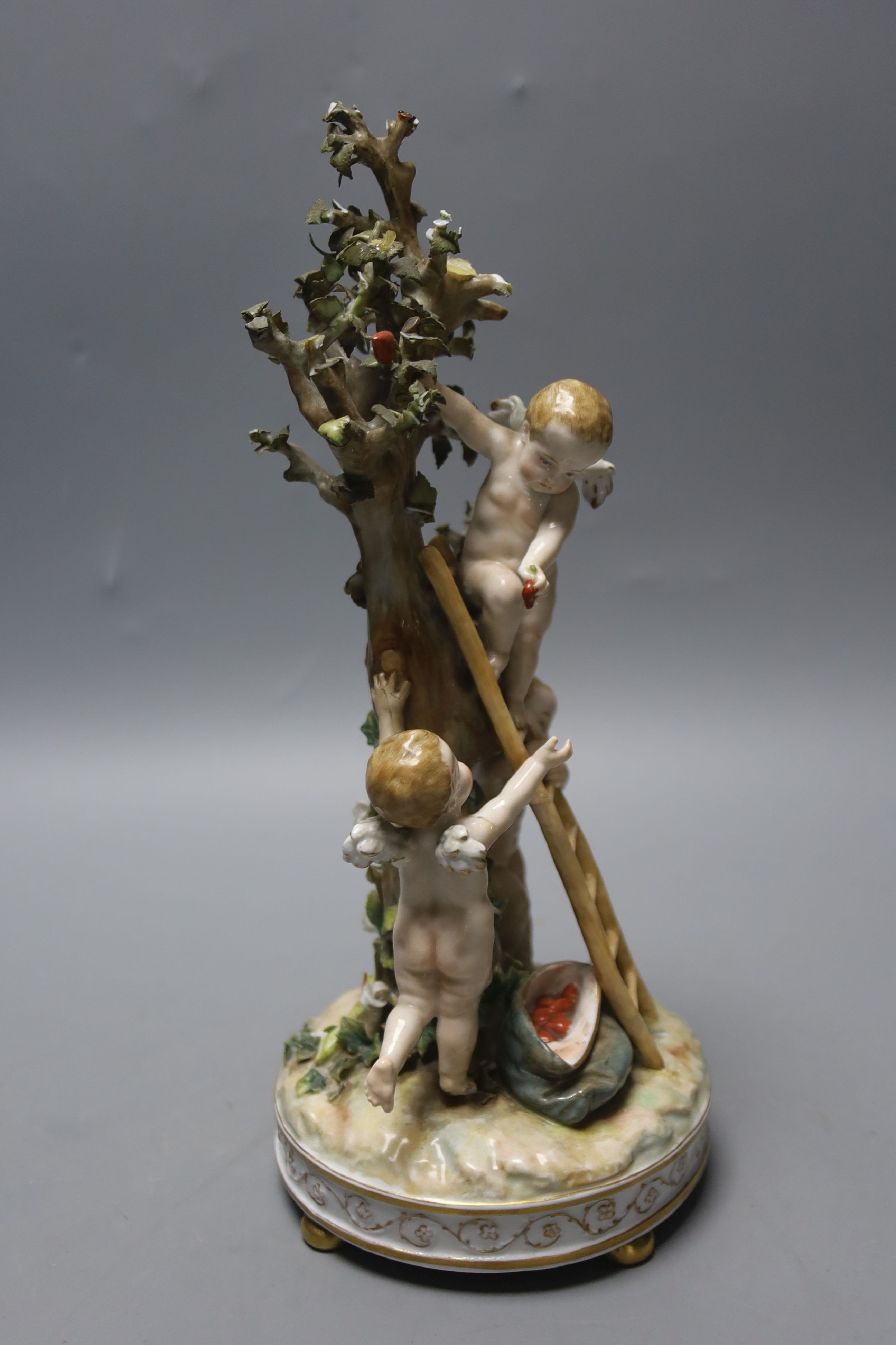 A German porcelain Meissen style group of amorini, climbing a ladder to pick fruit from a tree, small losses, 27cm